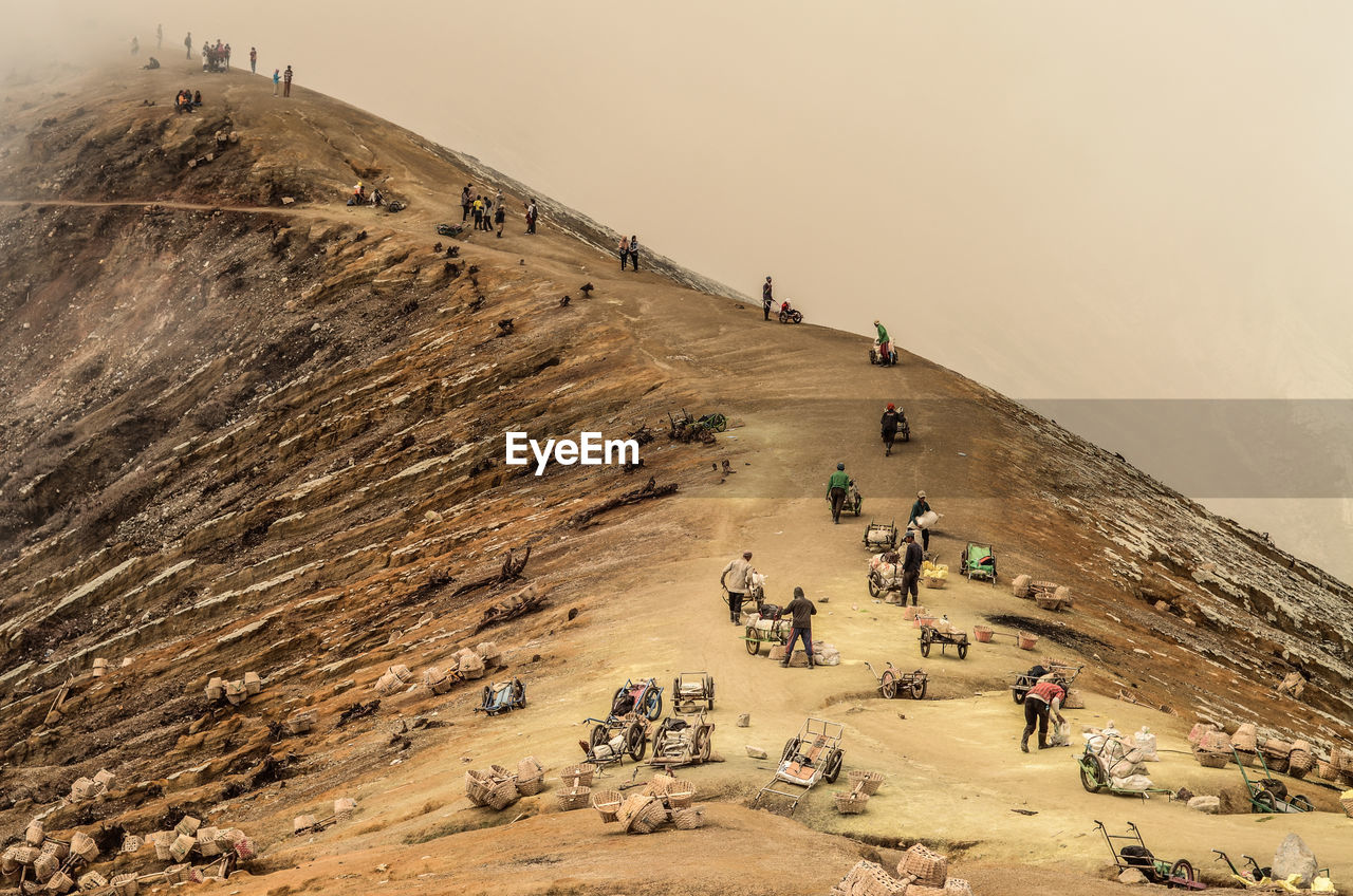 People working on mountain against sky