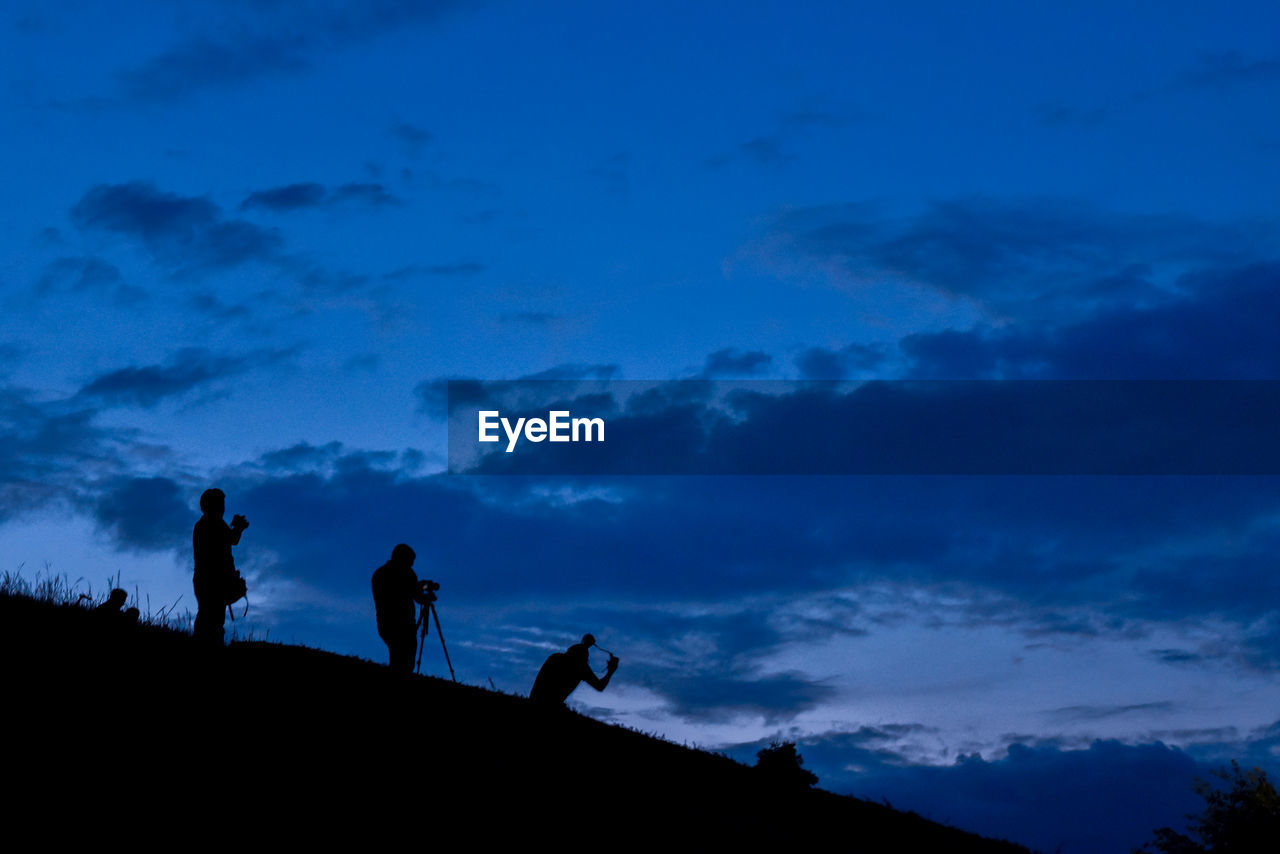 Low angle view of silhouette people against blue sky