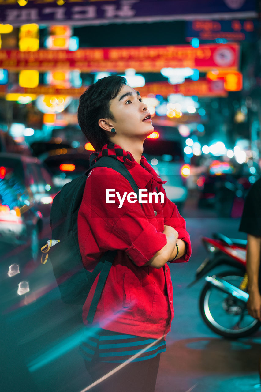 SIDE VIEW OF YOUNG WOMAN LOOKING AWAY AT NIGHT