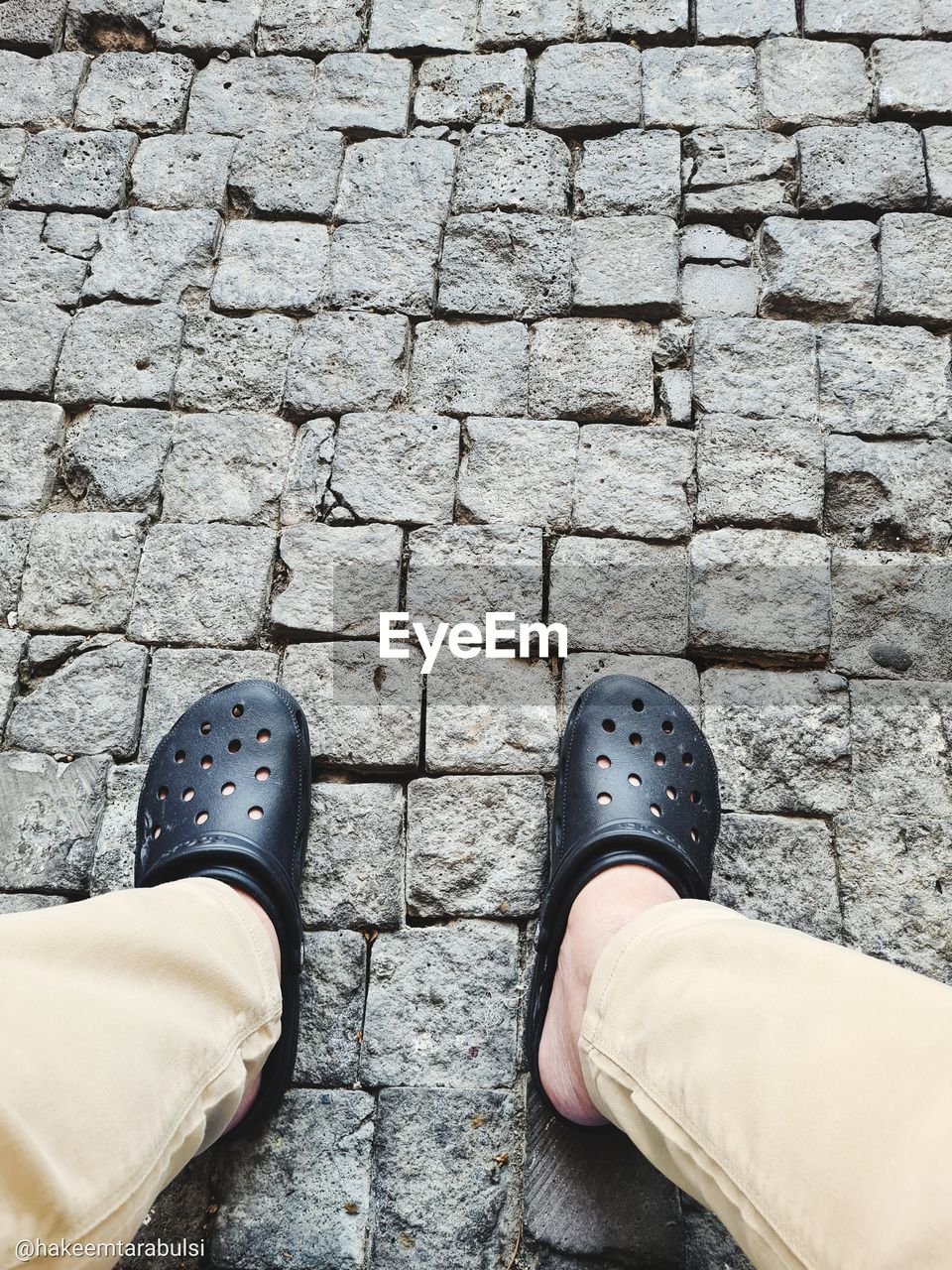 shoe, low section, human leg, personal perspective, one person, footwear, high angle view, lifestyles, standing, footpath, human limb, limb, day, street, leisure activity, men, wall, outdoors, cobblestone, city, human foot, adult, casual clothing, directly above