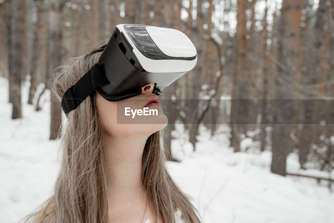 Woman wearing virtual reality simulator against trees outdoors