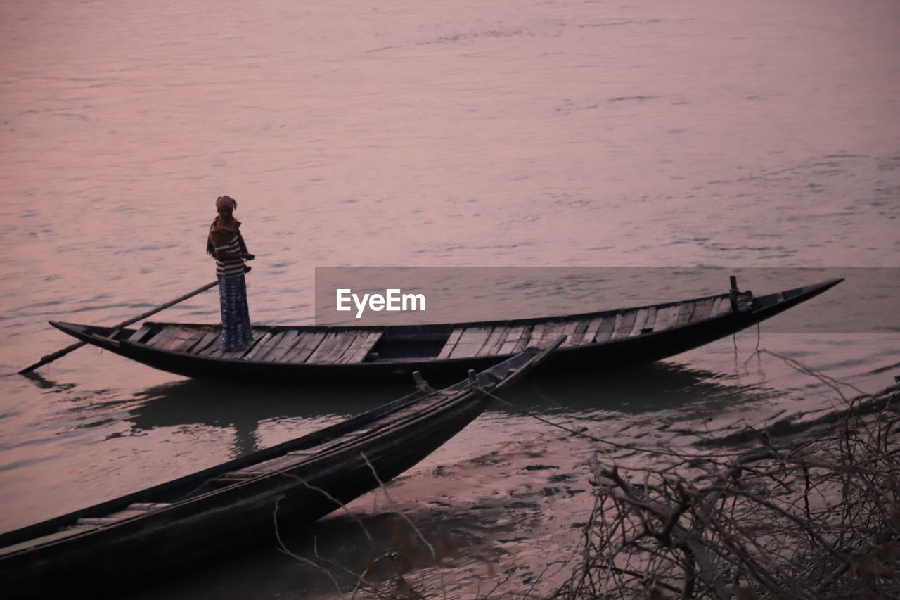 Man standing on boat in sea during sunset