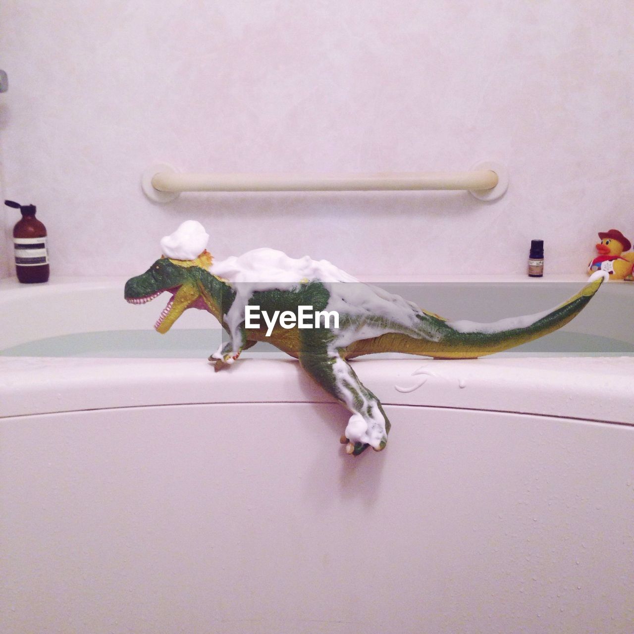 Toy dinosaur covered in foam at bathroom