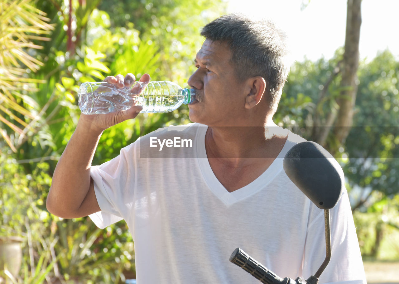 Senior asian people drinking purity water for quench thirst after finish work outdoor in hot day.