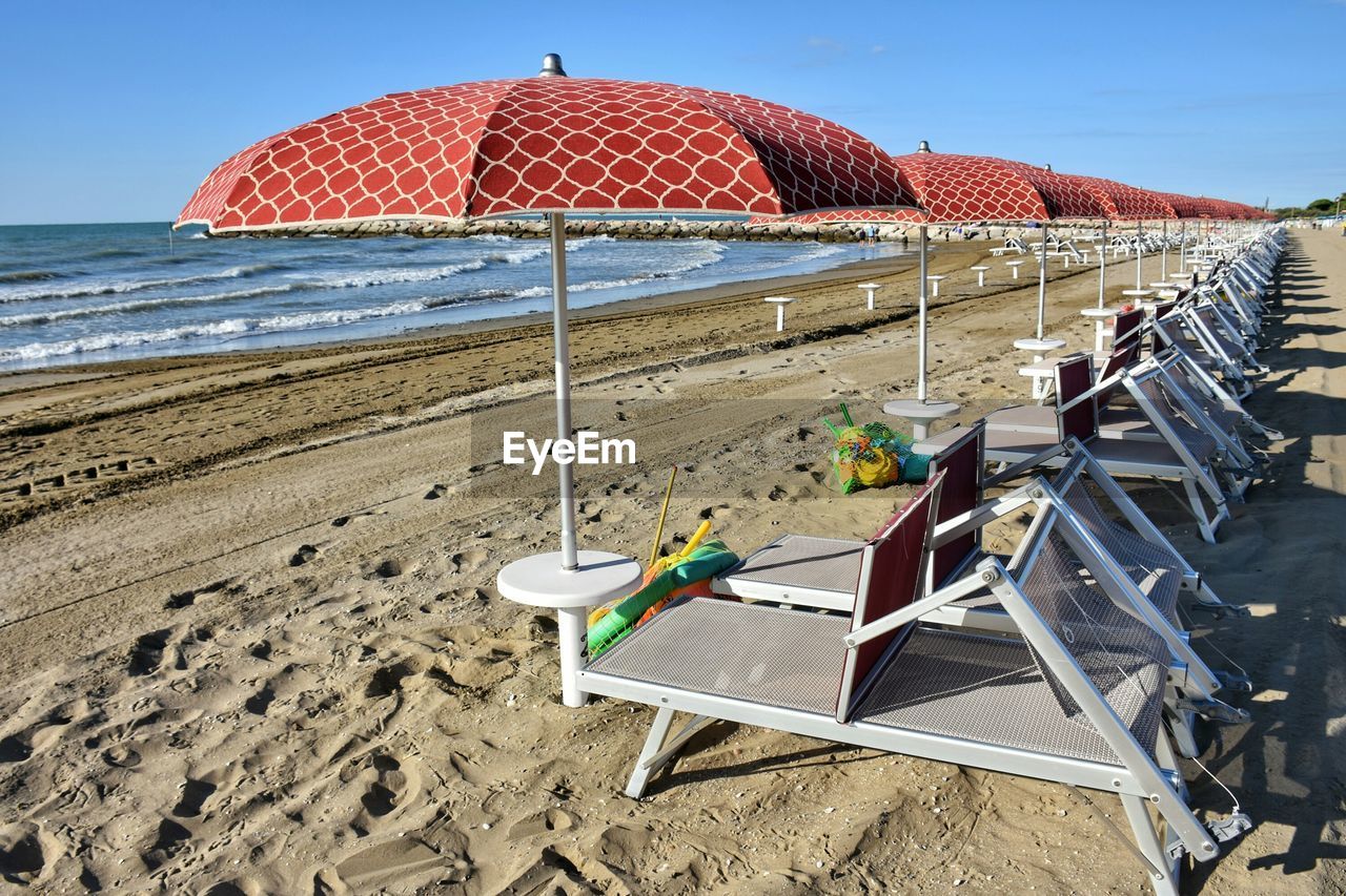 Deck chairs on beach against sky