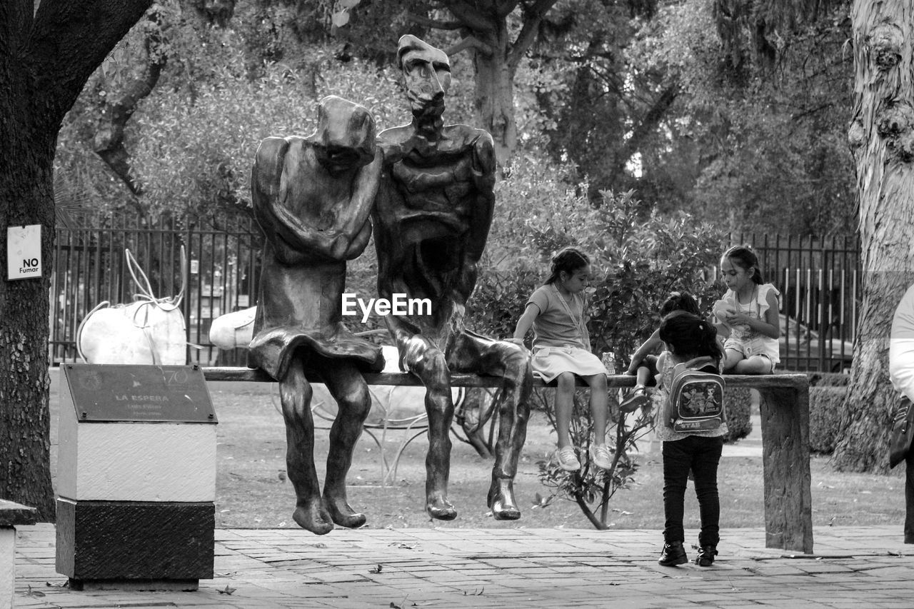 REAR VIEW OF PEOPLE STANDING ON TREE