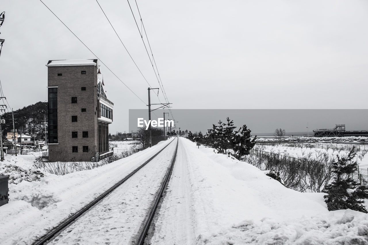 Snow covered railroad tracks against sky