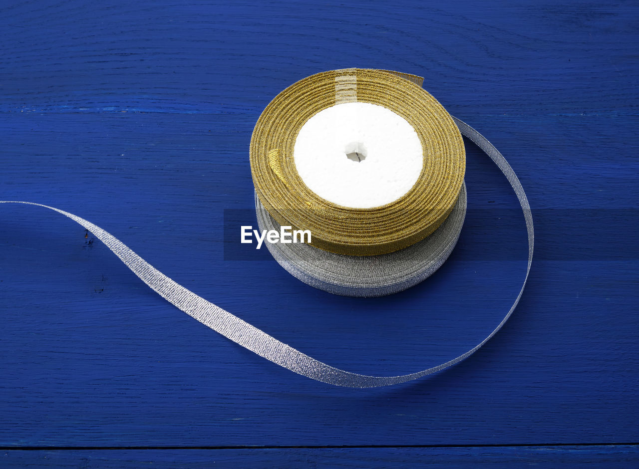 High angle view of rolled up ribbon over blue background