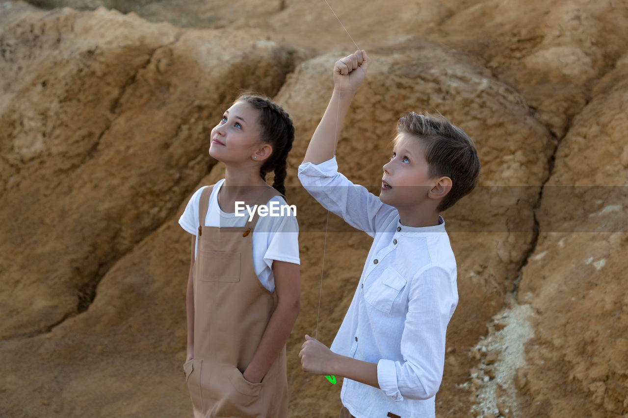 Children watching the flight of a kite with interest looking into the sky.