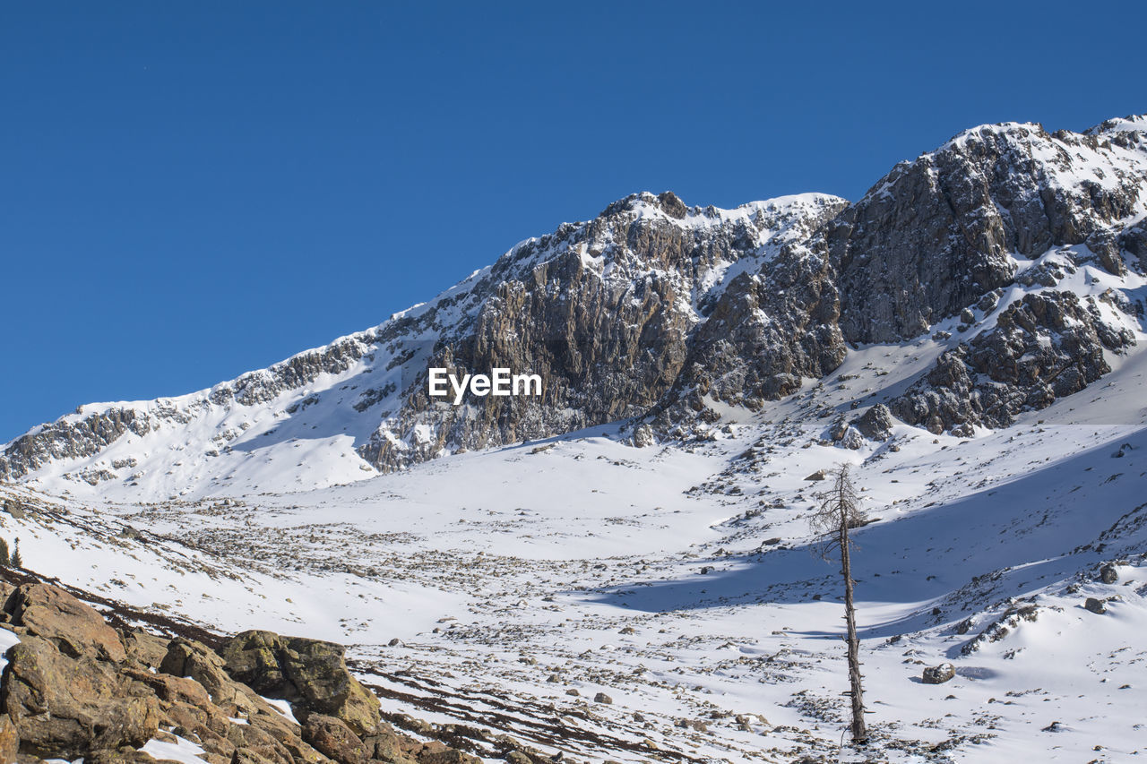 Scenic view of snowcapped mountains against clear blue sky