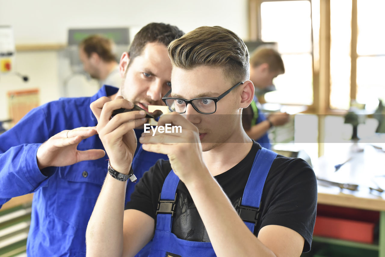 Instructor examining workpiece of trainee