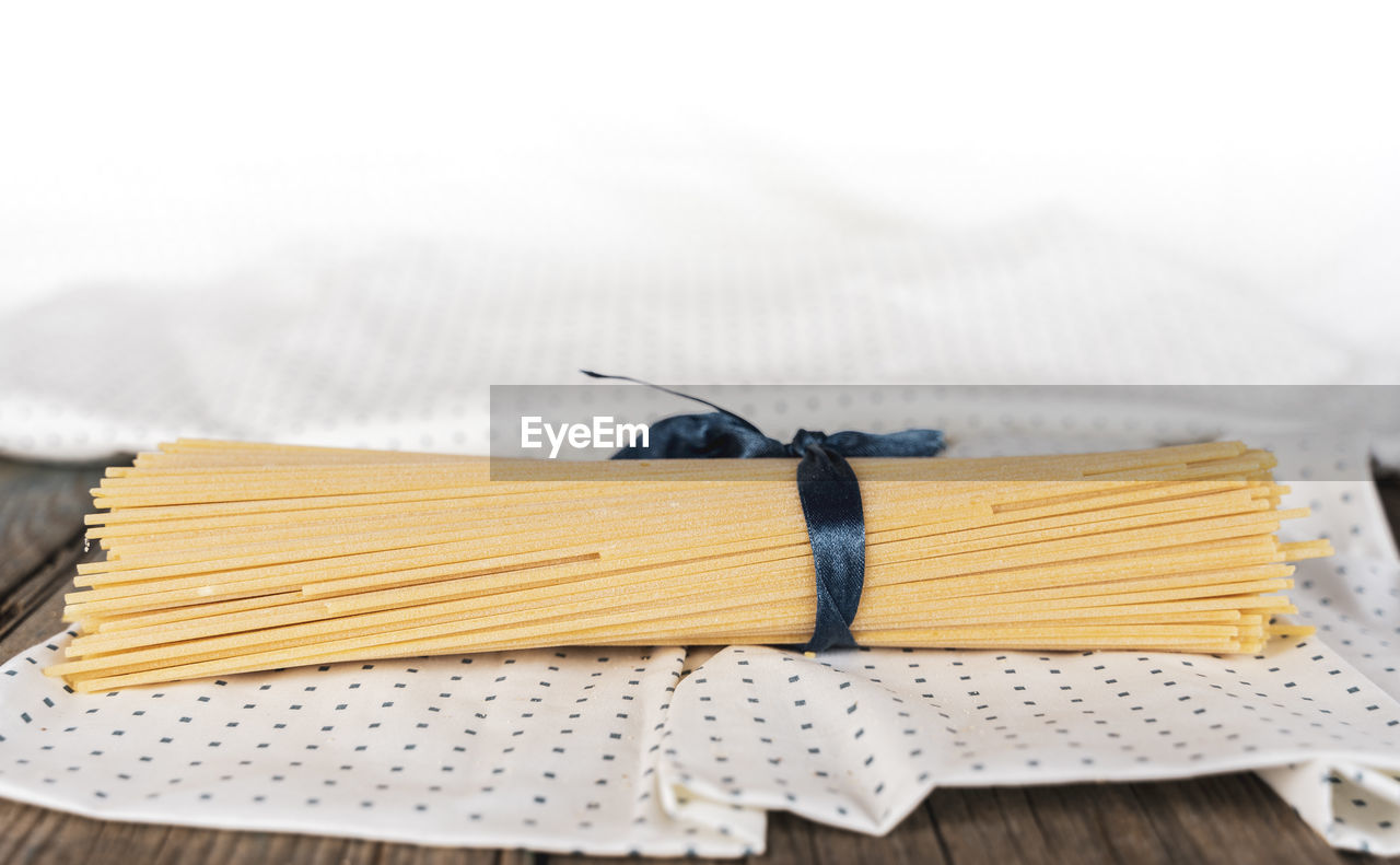 Group of uncooked italian spaghetti pasta tied together by blue silk ribbon on cloth background