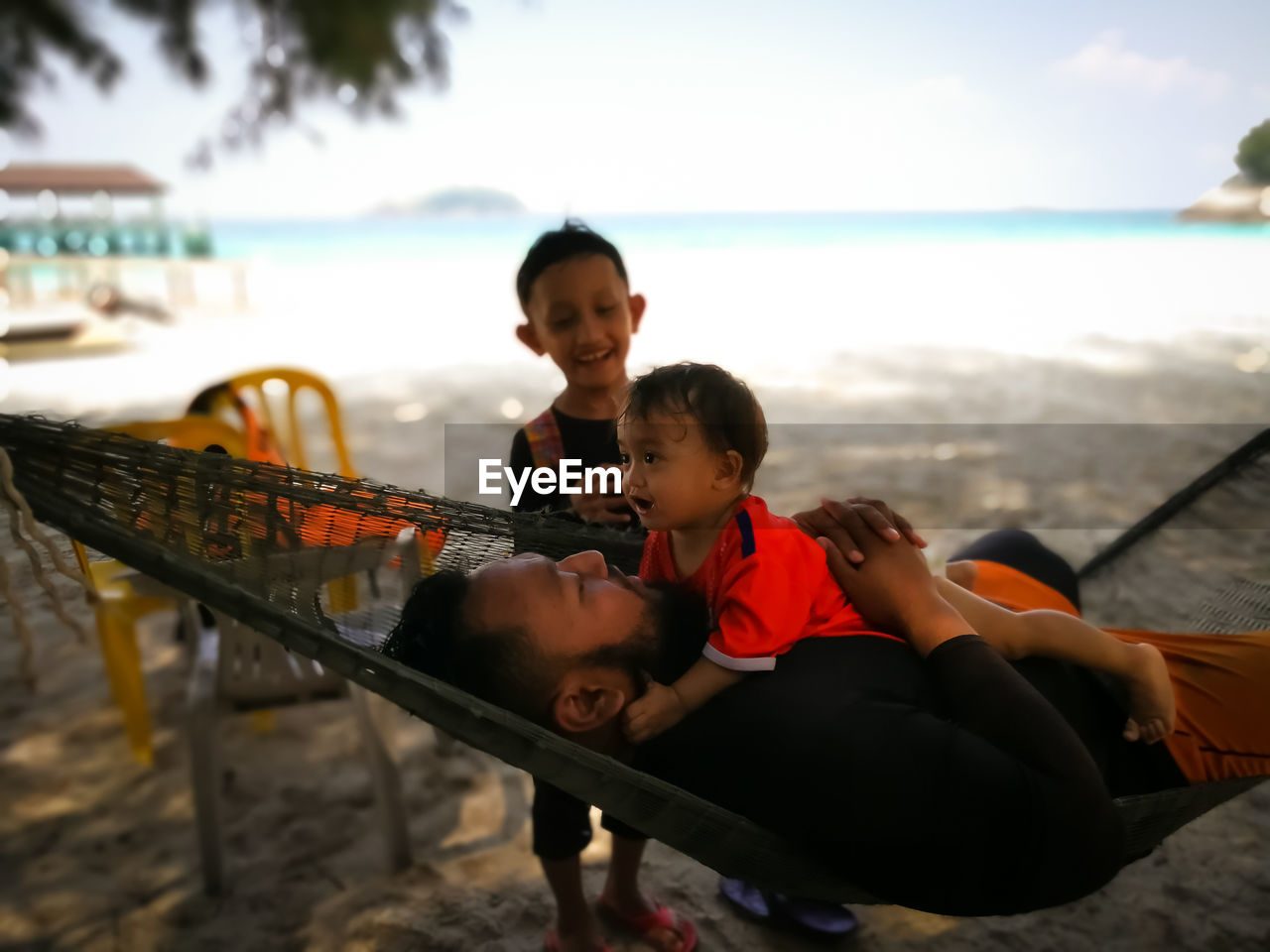 Father embracing daughter by siblings at beach