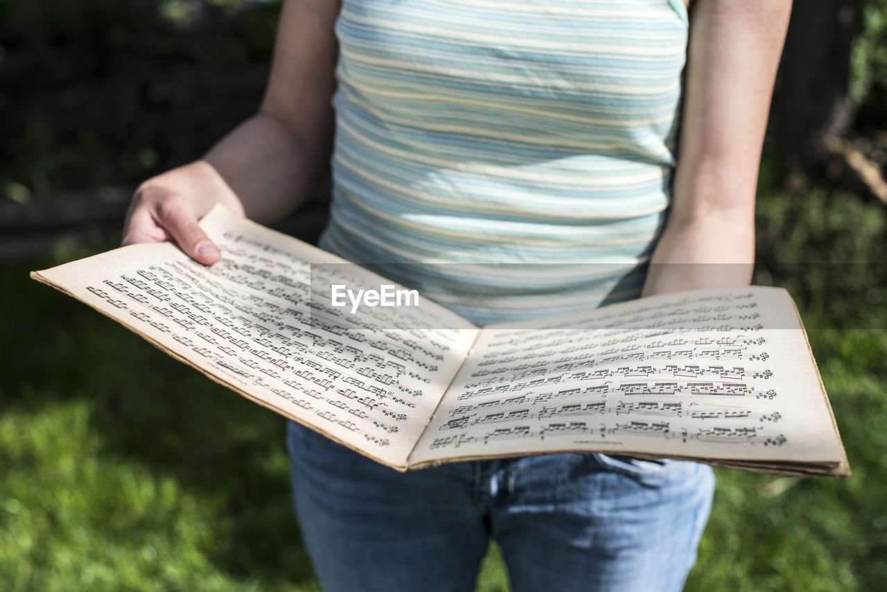 Midsection of woman holding sheet music