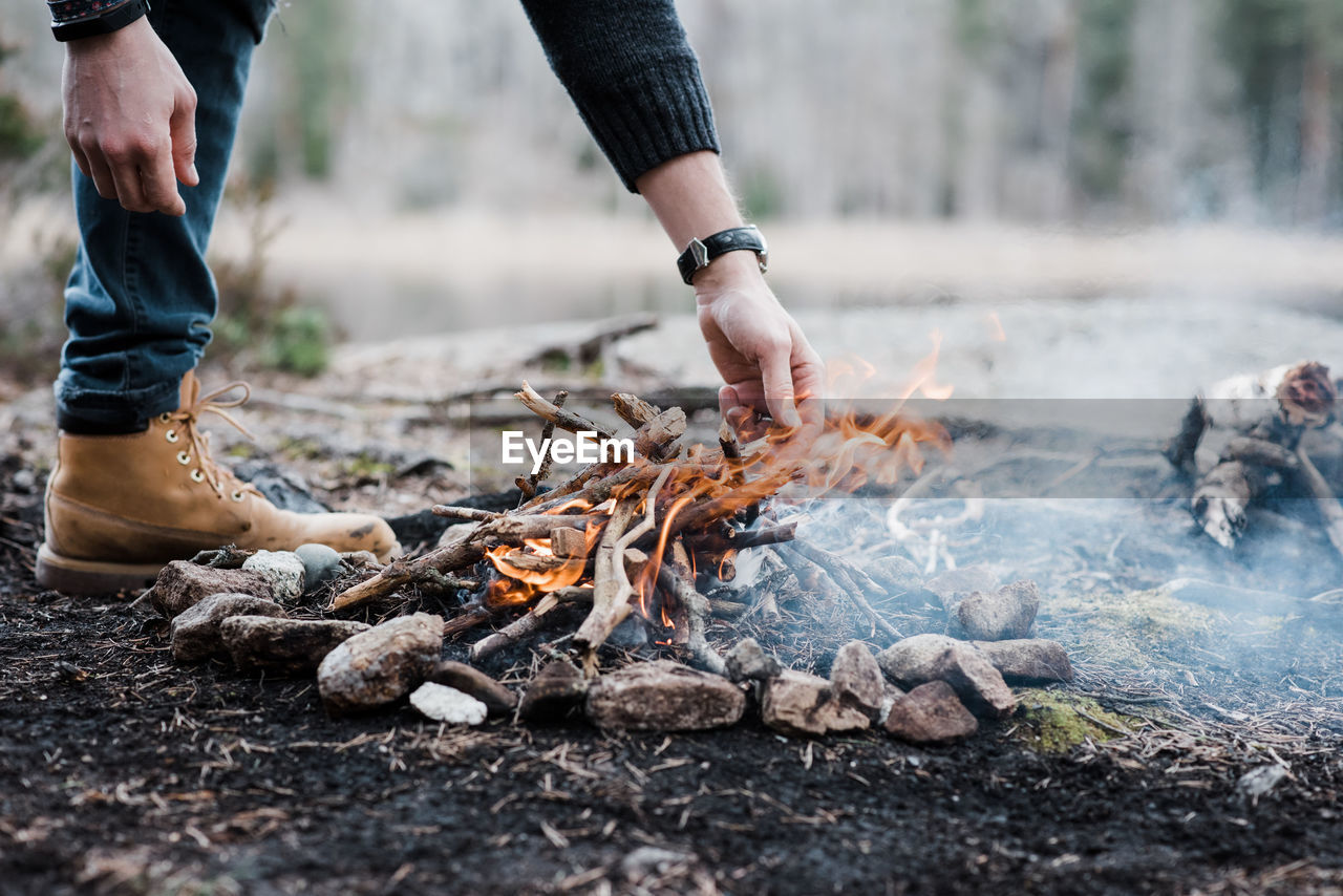 Man putting logs on a handmade campfire outdoors in sweden