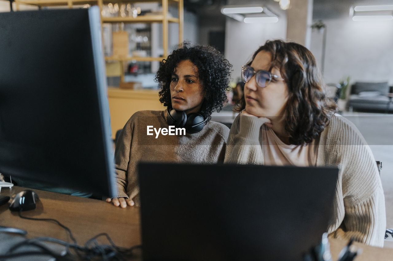 Dedicated female programmers using computer while working at desk in creative workplace