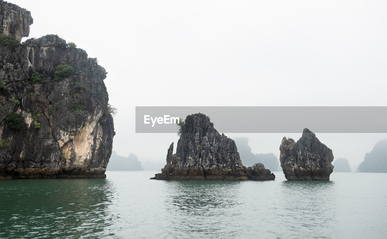 Rock formations in sea against clear sky