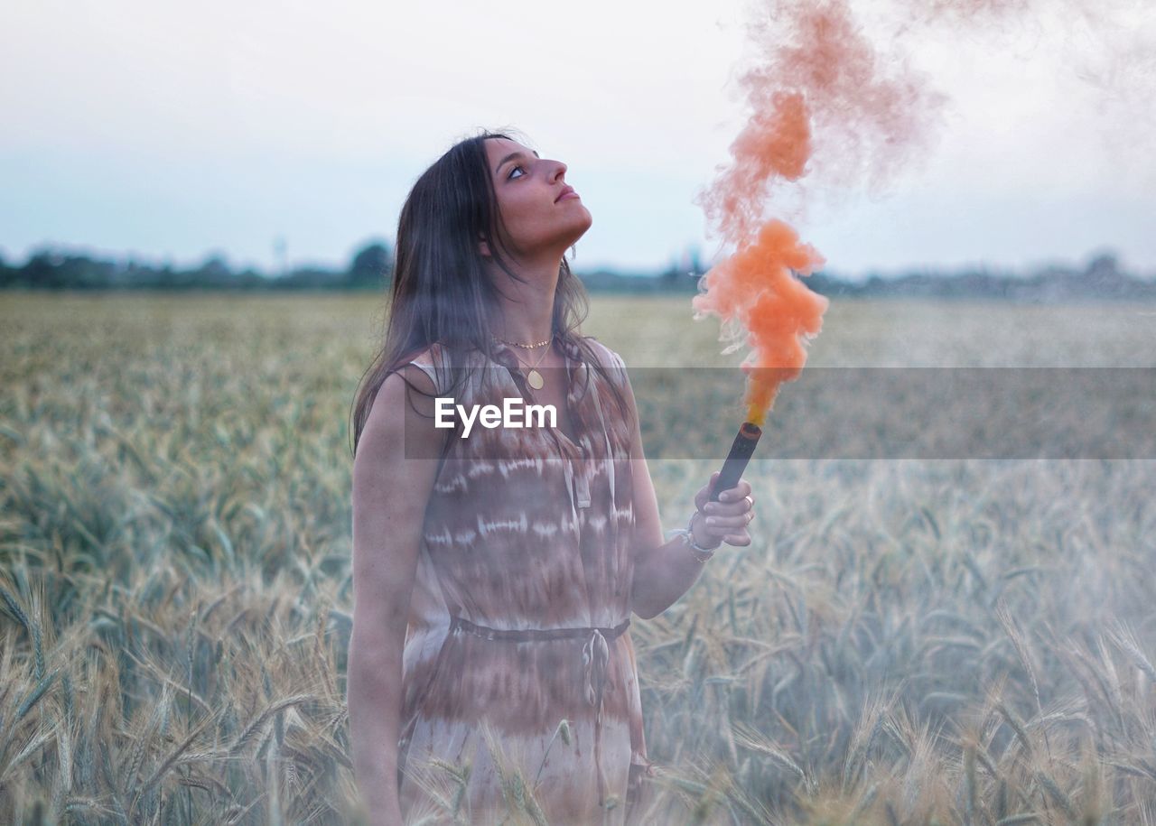 Young woman standing on field with a smoke granade 