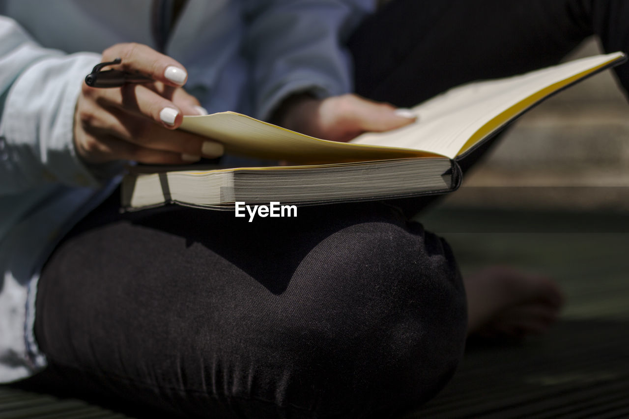 Midsection of woman reading book