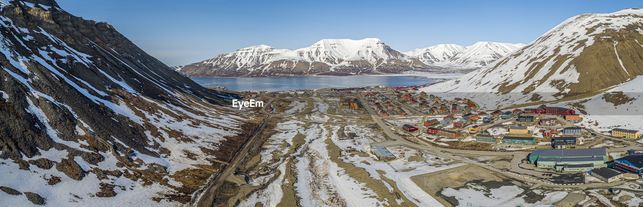 Scenic view of townscape by snowcapped mountains against sky