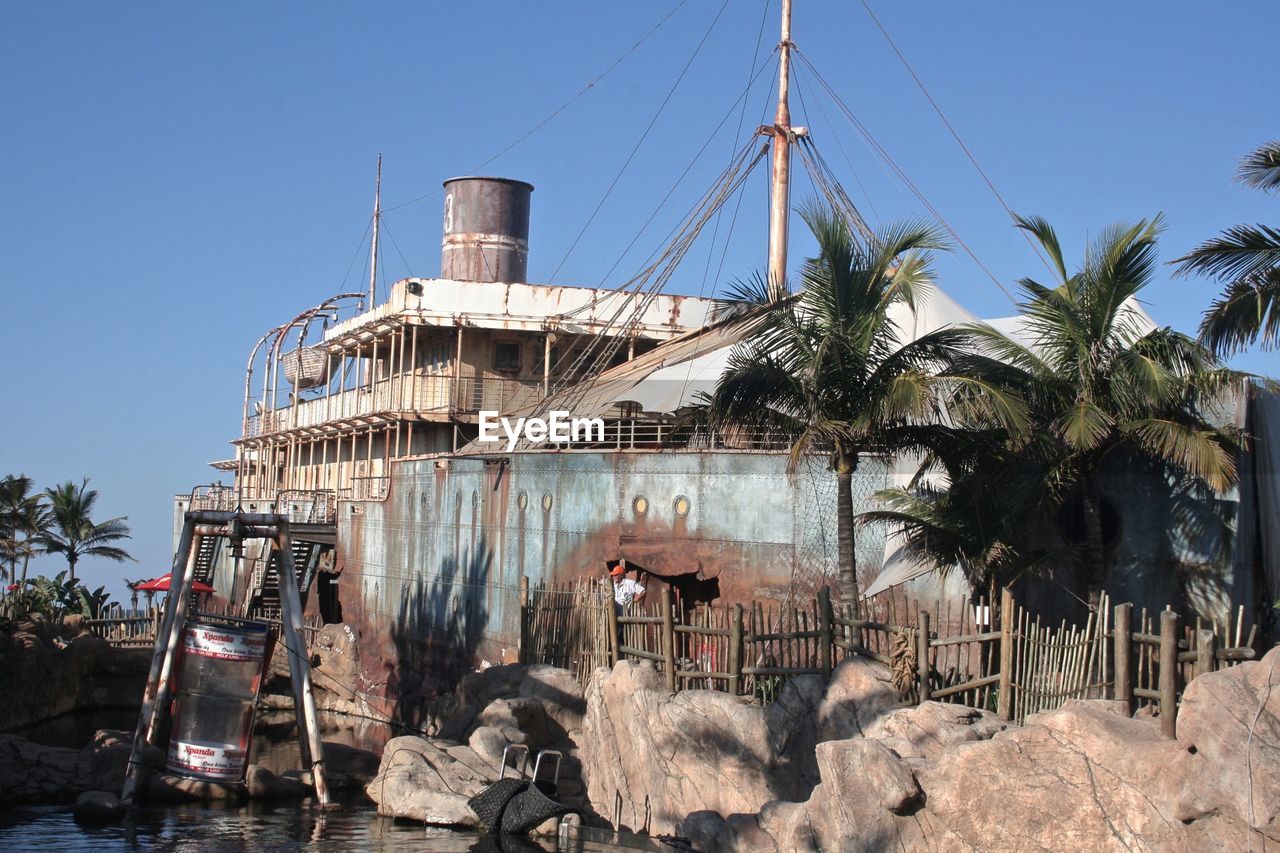 Abandoned ship moored at shore against clear blue sky