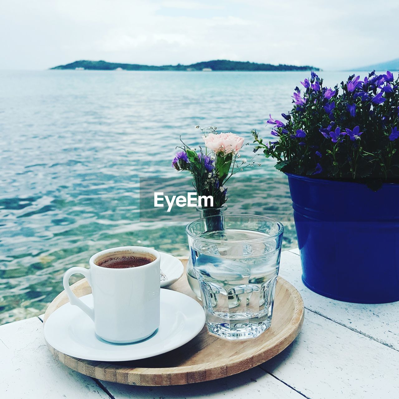 Close-up of turkish coffee with vase and potted plant by sea