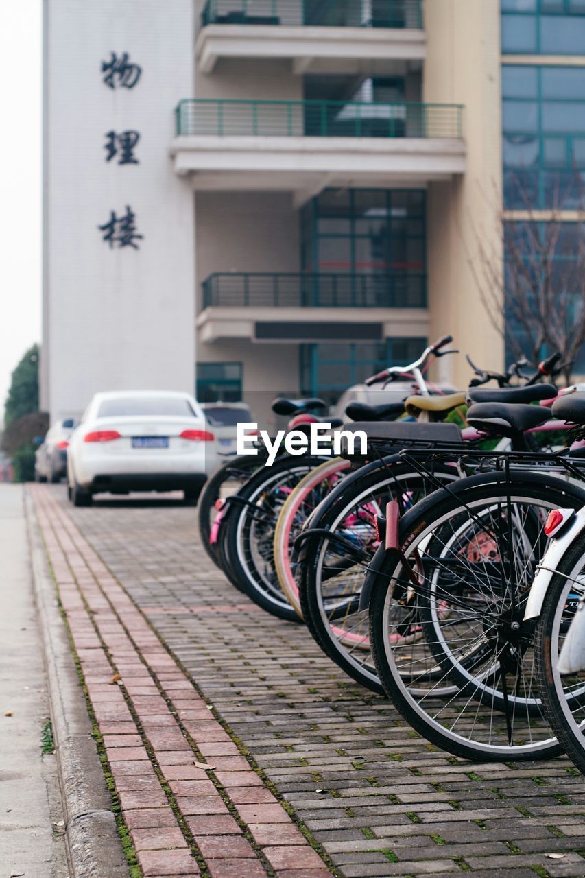 Bicycles parked in row on sidewalk against building