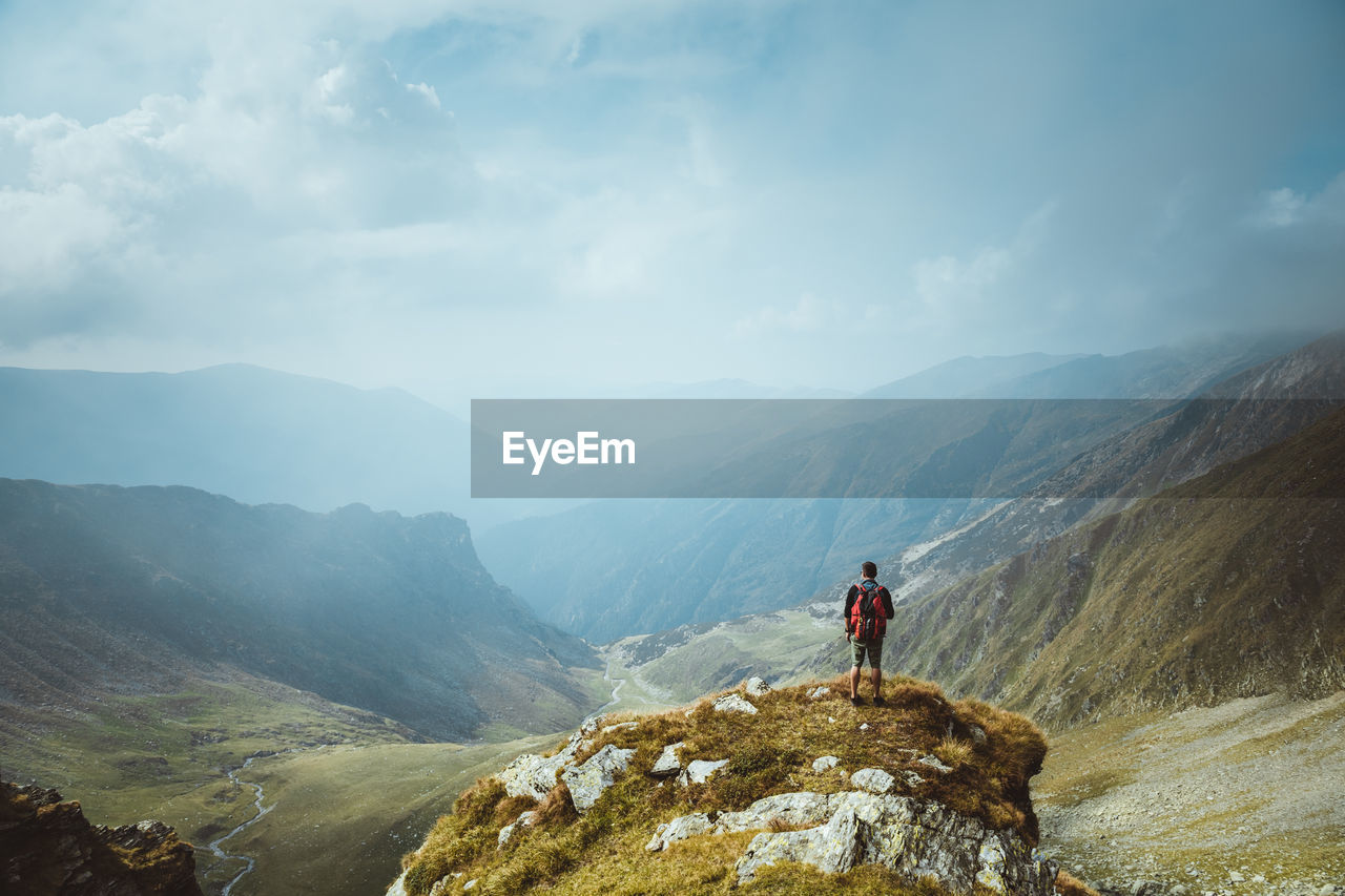 Man looking at mountains against sky