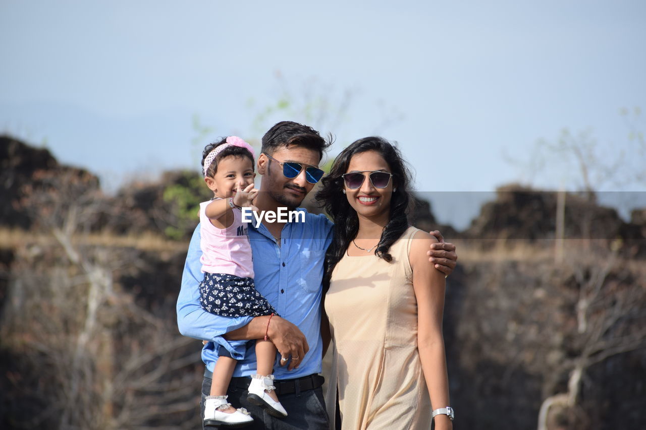 Portrait of happy family standing against sky