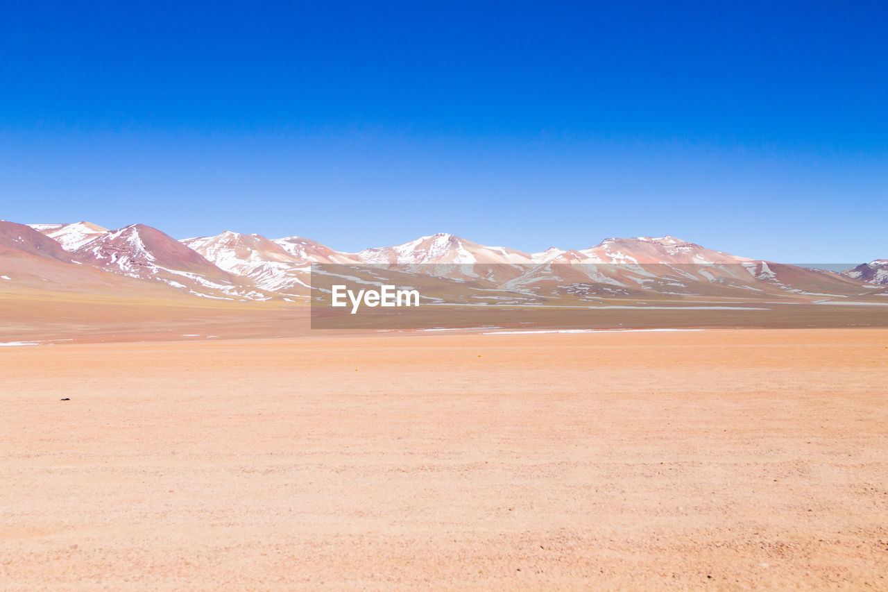 Scenic view of snowcapped mountains against clear blue sky