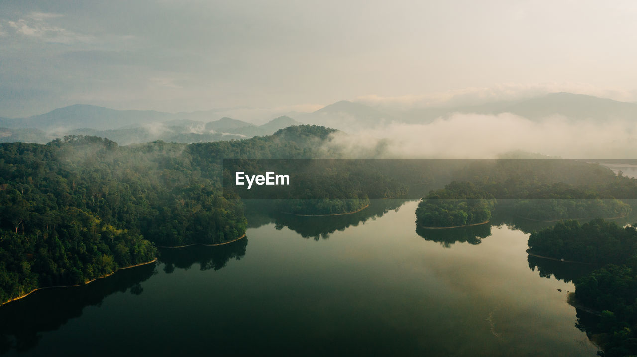 Scenic view of lake by trees against sky