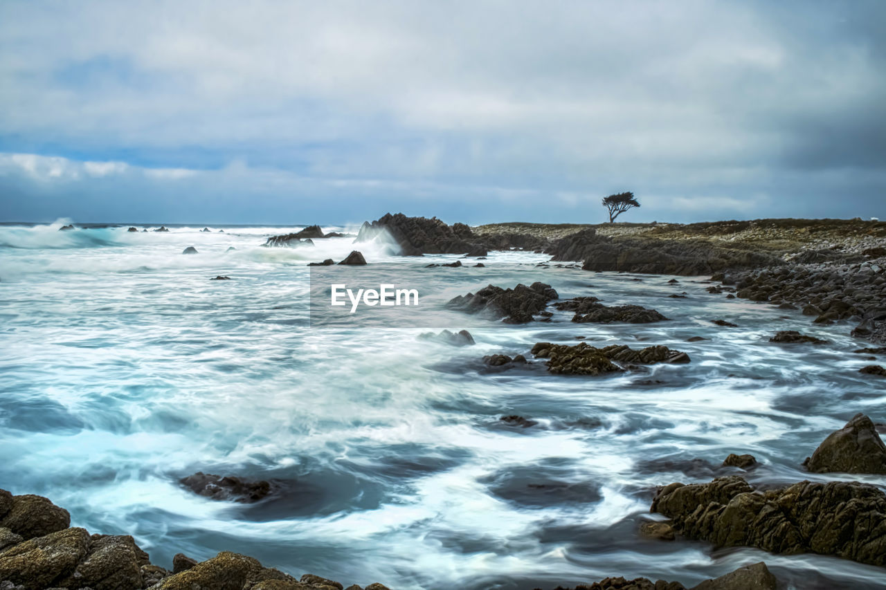 SCENIC VIEW OF WAVES BREAKING AGAINST ROCKS