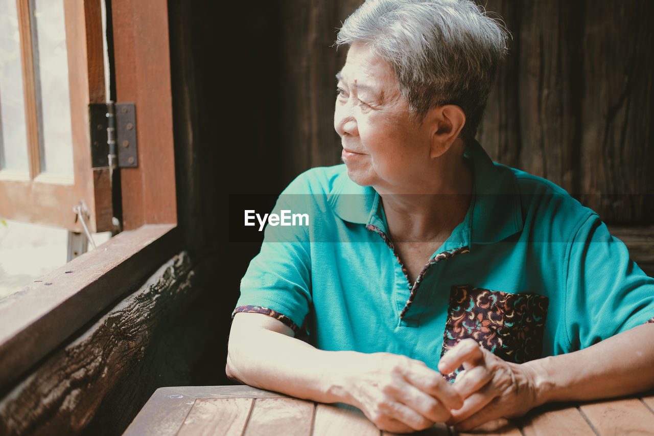 Asian elderly female elder woman sitting near window at home. senior leisure lifestyle