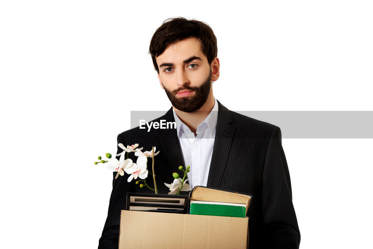 Portrait of businessman with objects standing against white background