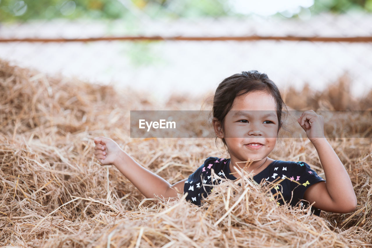 Smiling girl sitting on hay 