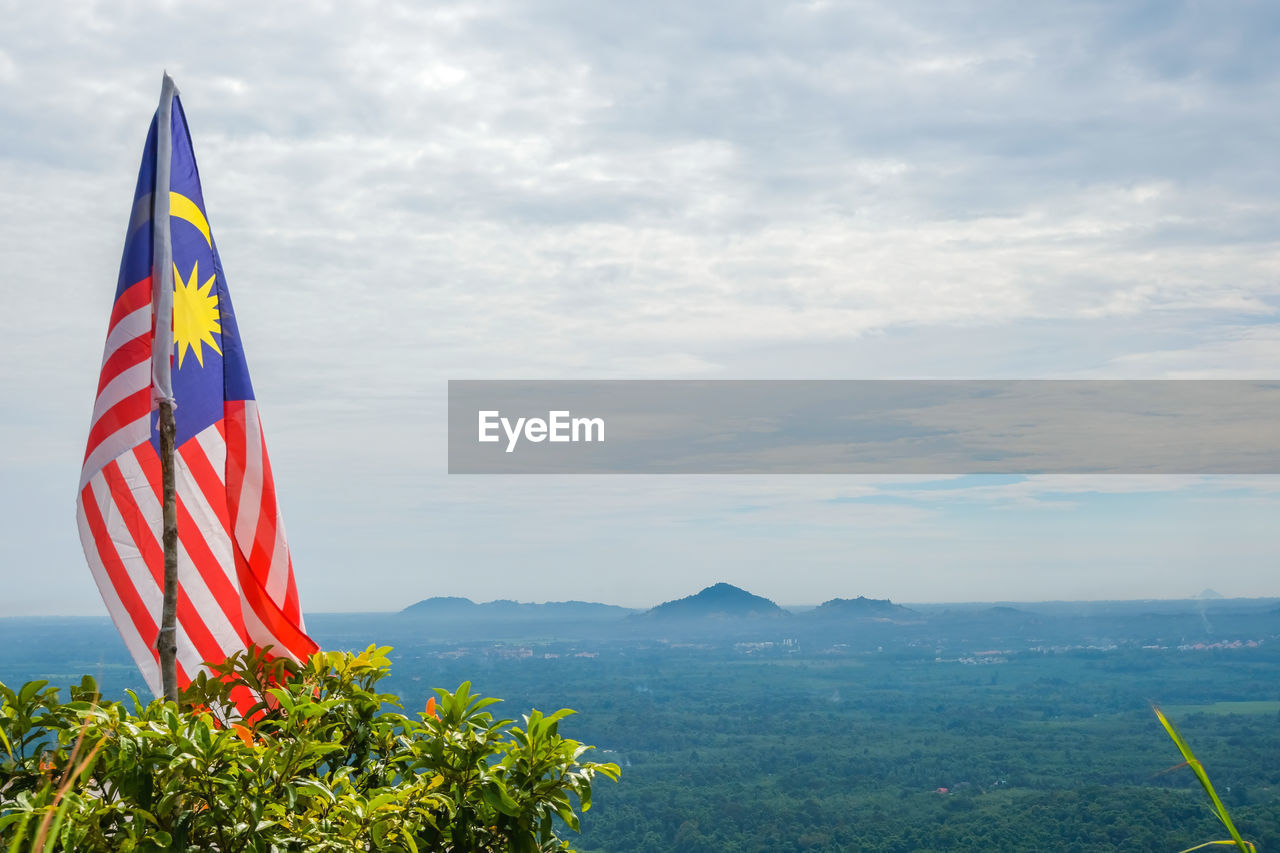 Malaysia flag on landscape against sky in panau hill, kelantan, malaysia.