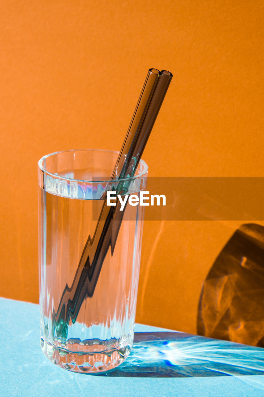 Reusable glass straws in glass with water on colorful background eco-friendly drinking straw set