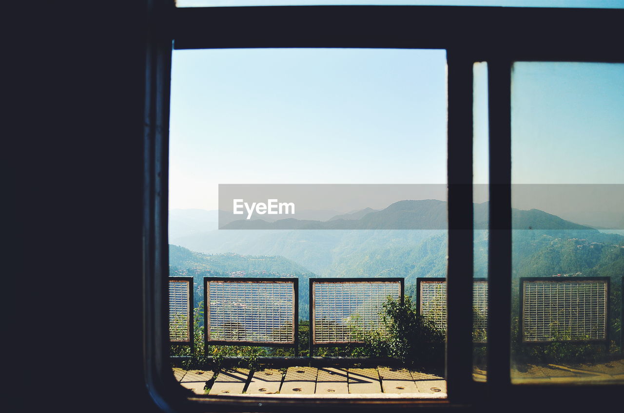 Mountains against sky seen through train window