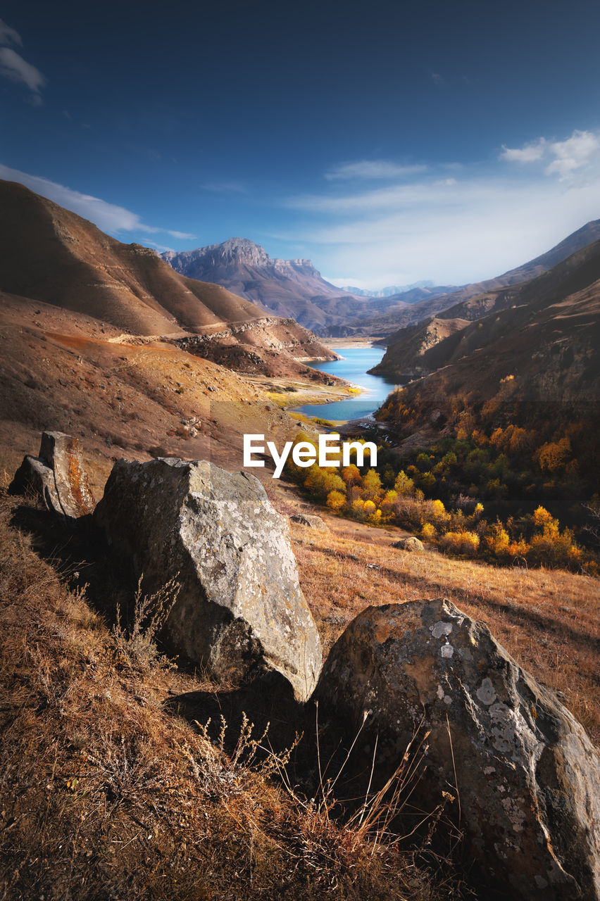 Landscape of beauty autumn day in mountain lake with stones at the front. vertical view of epic