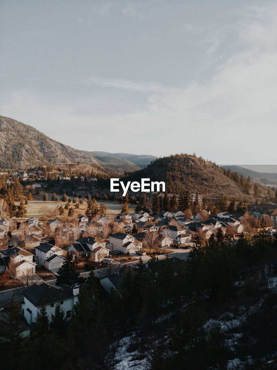 Scenic view of townscape by mountains against sky