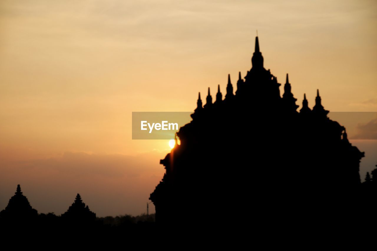 SILHOUETTE TEMPLE AGAINST BUILDINGS DURING SUNSET