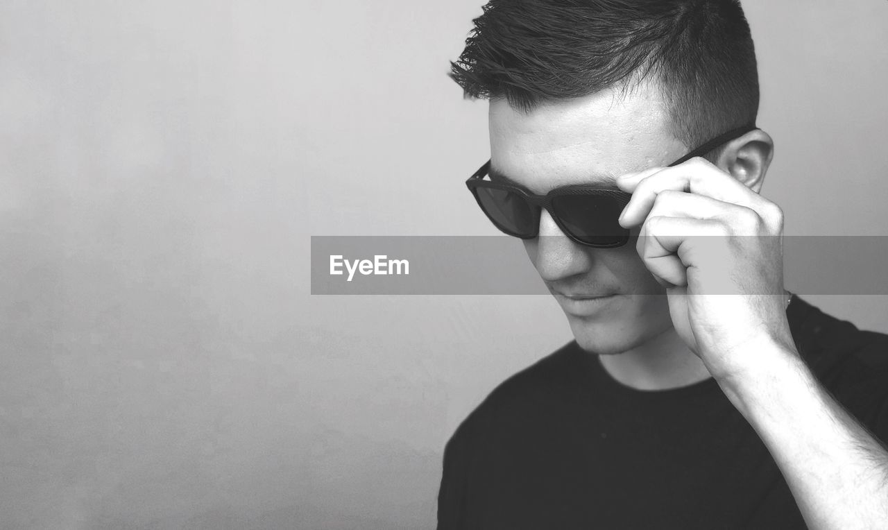 Close-up of young man wearing sunglasses against gray background
