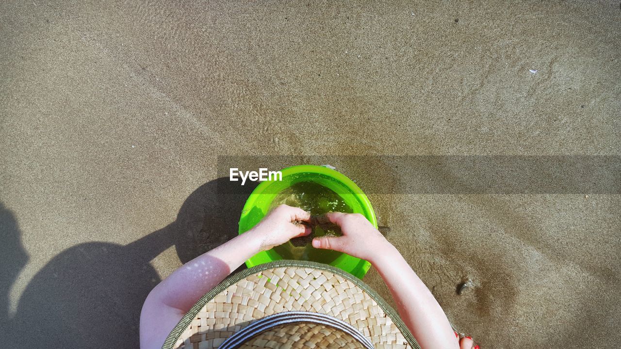 Cropped image of boy with bucket at beach