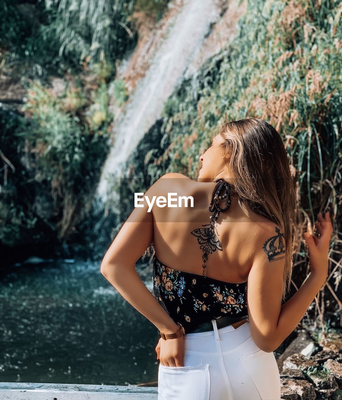 Rear view of young woman standing by waterfall