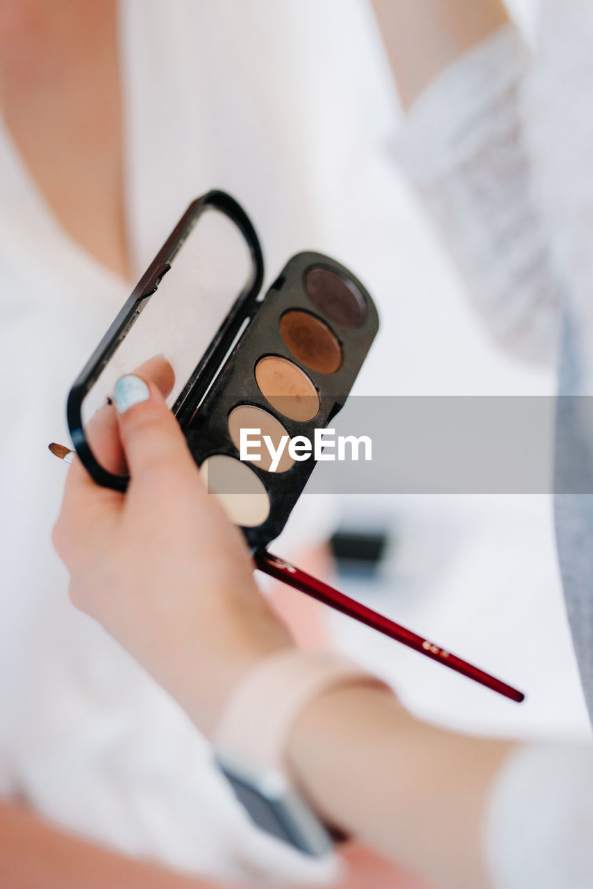 Cropped hand of woman holding make up box