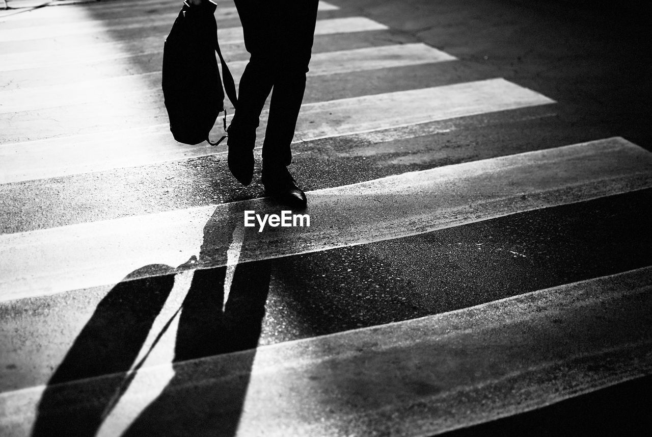Low section of man walking on zebra crossing