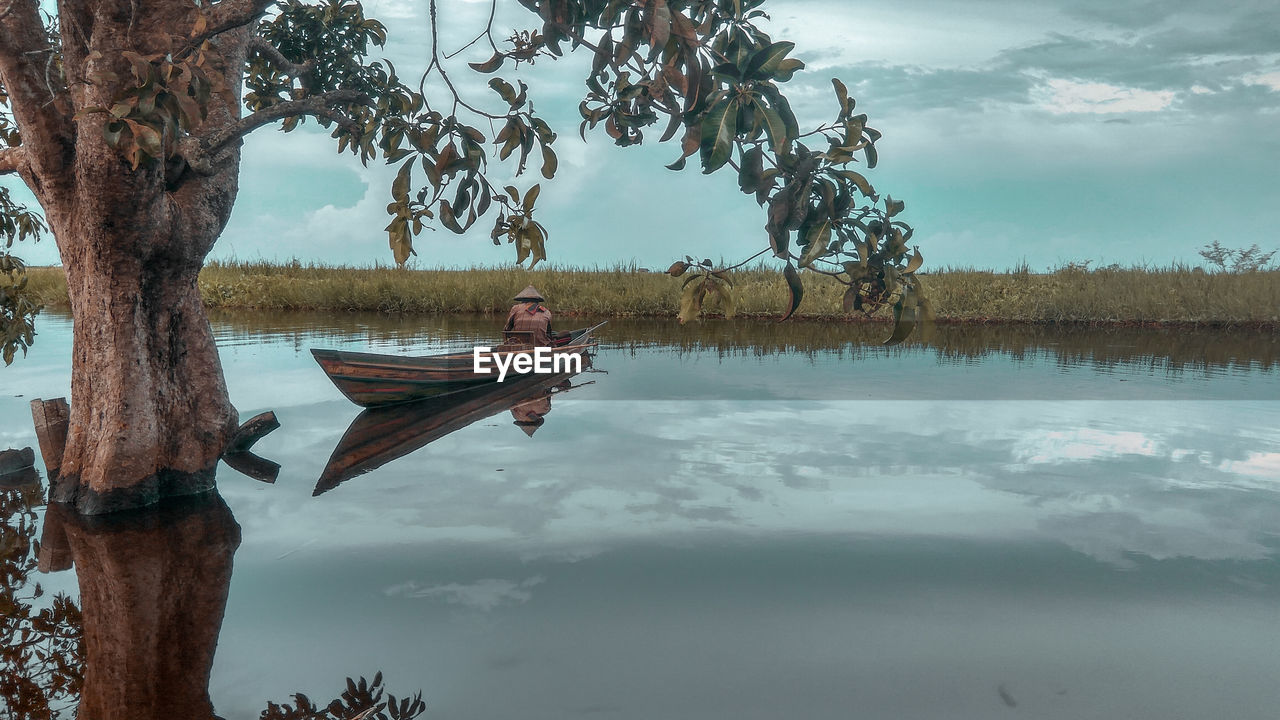 Man on boat in lake against sky