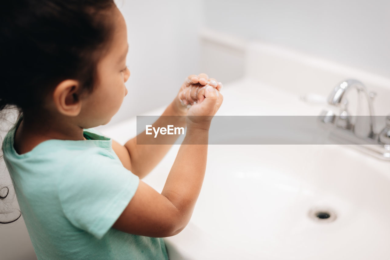 Cute girl washing hand at sink