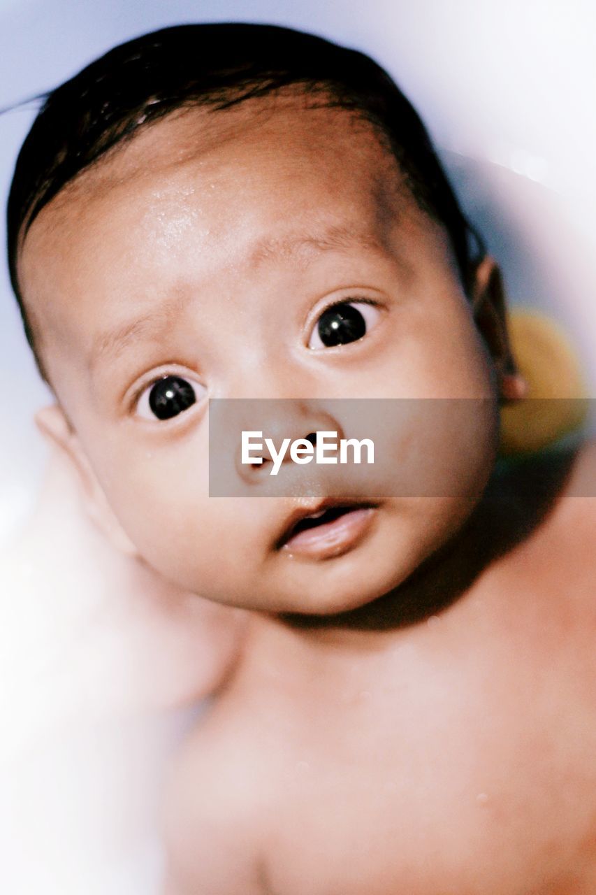 Close-up portrait of shirtless cute baby boy in bathtub