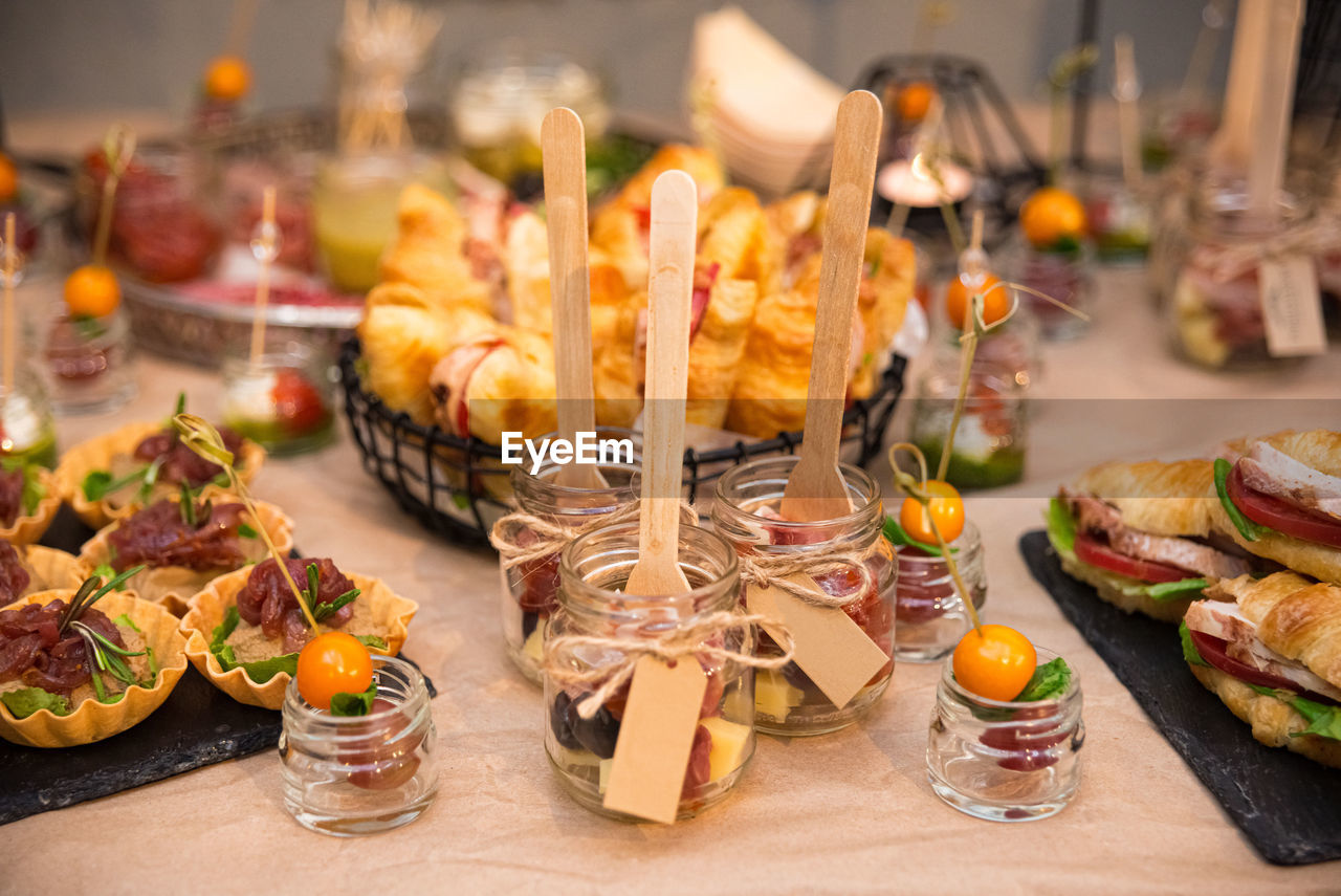 Catering in jars with wooden forks. lots of cold snacks, croissant sandwiches, tartlets, canapés